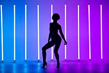 Young Stylish Girl Dancing In The Studio On A Colored Background With Neon Lighting Lamp. Music Dj Poster Design. Dark Royalty Free Stock Image