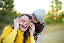 Happy Young Girl Laughing, Covering Eyes Of Her Mother With Her Hand. Royalty Free Stock Images