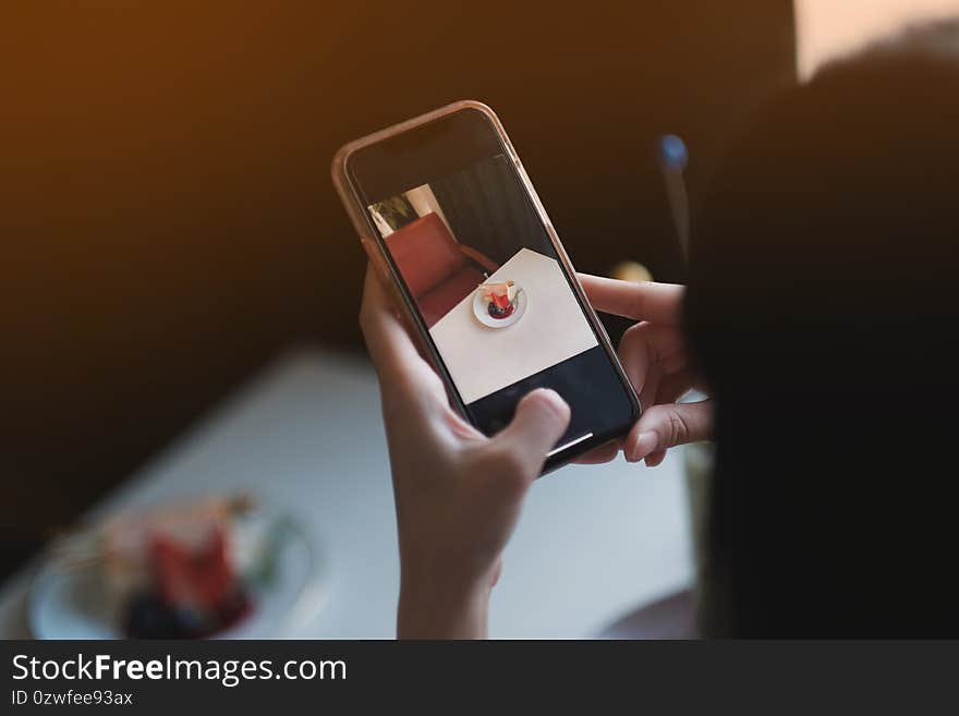 A girl take a picture some food by smartphone in restaurant