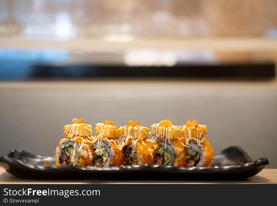 Maki sushi salmon roe on top with tamako served on black tray. Selective focus. Japanese traditional food