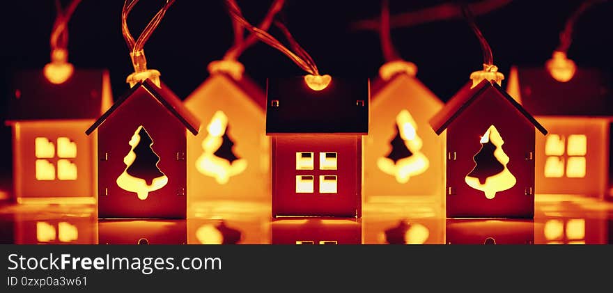 house and Christmas tree shape garlands, illuminated glow light at night