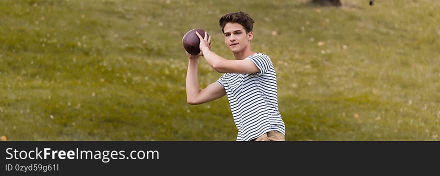 Panoramic crop of teenager boy playing american football in park