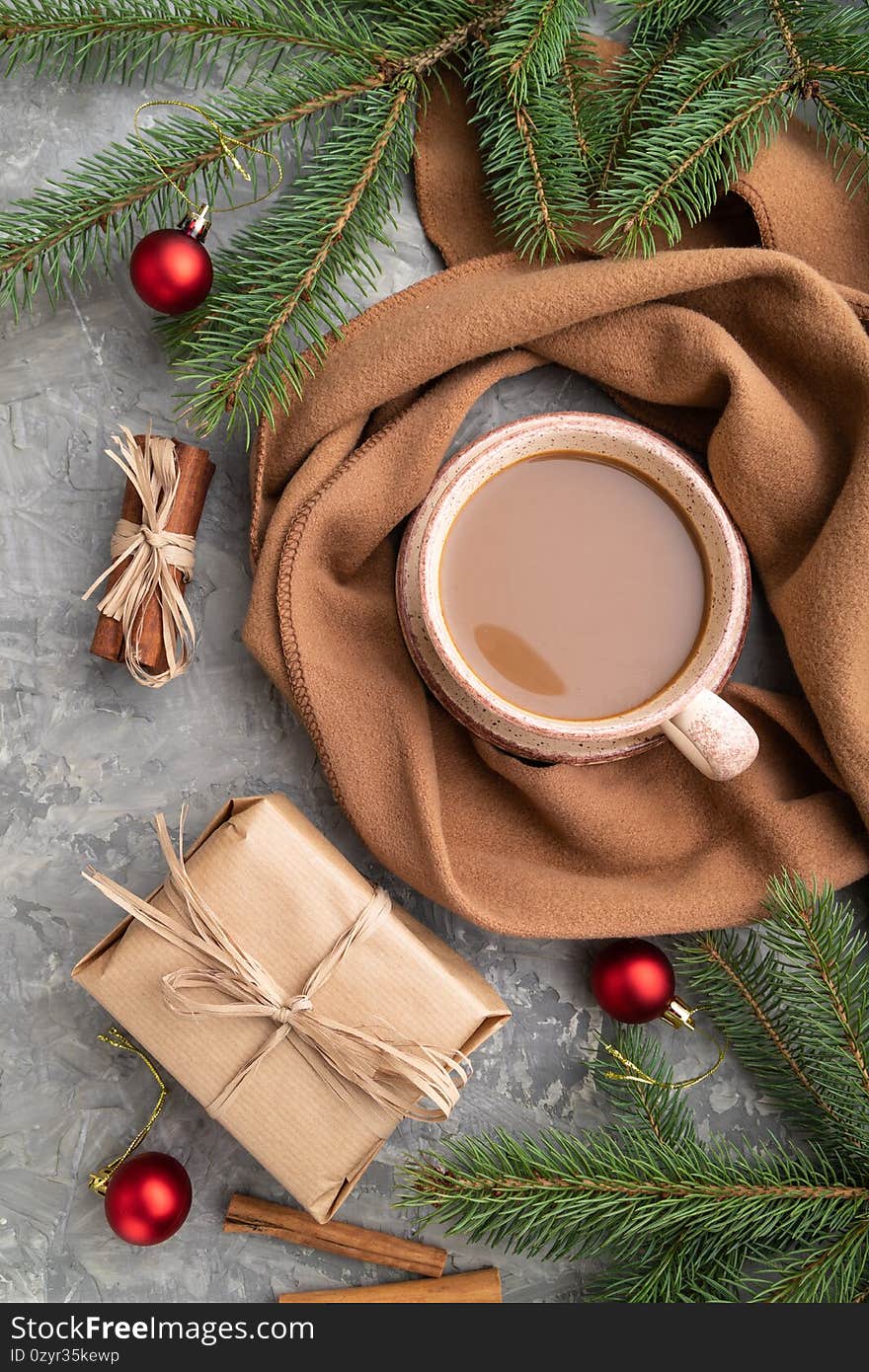 Christmas or New Year composition. Decorations, fir and spruce branches, cup of coffee, on a gray concrete background. Top view