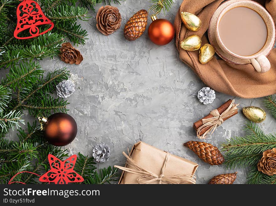 Christmas or New Year frame composition. Decorations, cones, fir and spruce branches, cup of coffee, on a gray concrete background