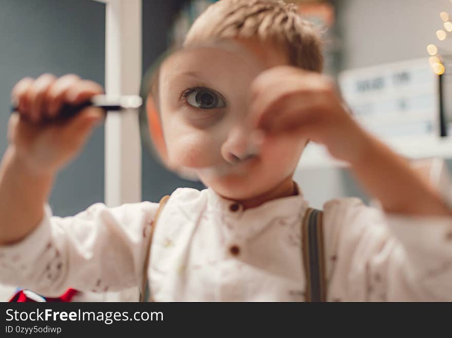 Young boy with loupe, playing at home