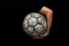 Old Soccer Ball In The Hands Of A Teenager On A Black Background. Stock Photo