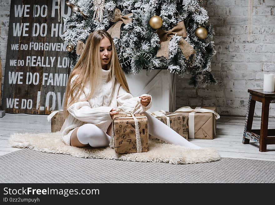 Young beautiful woman model with long hair in leggings long sweater christmas tree christmas light interior new year holiday. holiday card, party mood, congratulations spruce