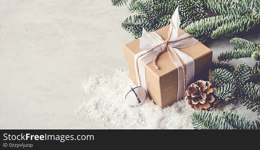 Christmas gift box in the snow on gray background. Christmas decor, winter mood, holiday decoration