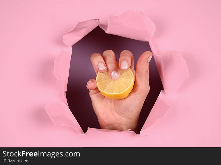 Hand holds lemon on a pink background