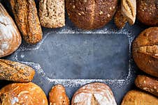 Banner With Different Types Of Fresh Bread Surrounded By A Silhouette Wooden Cutting Board On A Gray Surface, Top View, Copy Space Royalty Free Stock Photography