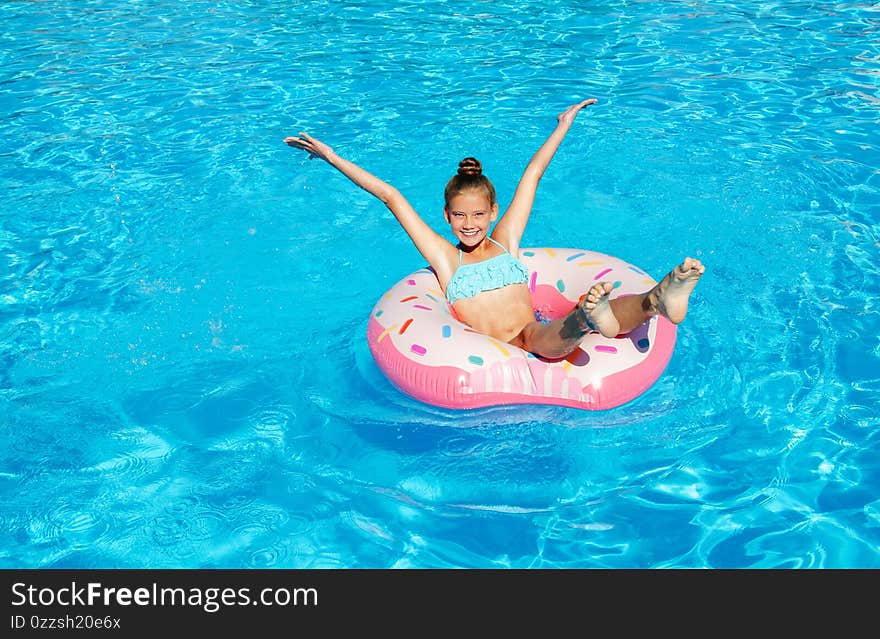 Cute smiling little girl in swimming pool with rubber ring