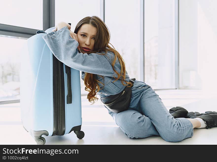 Girl at home near overloaded suitcase