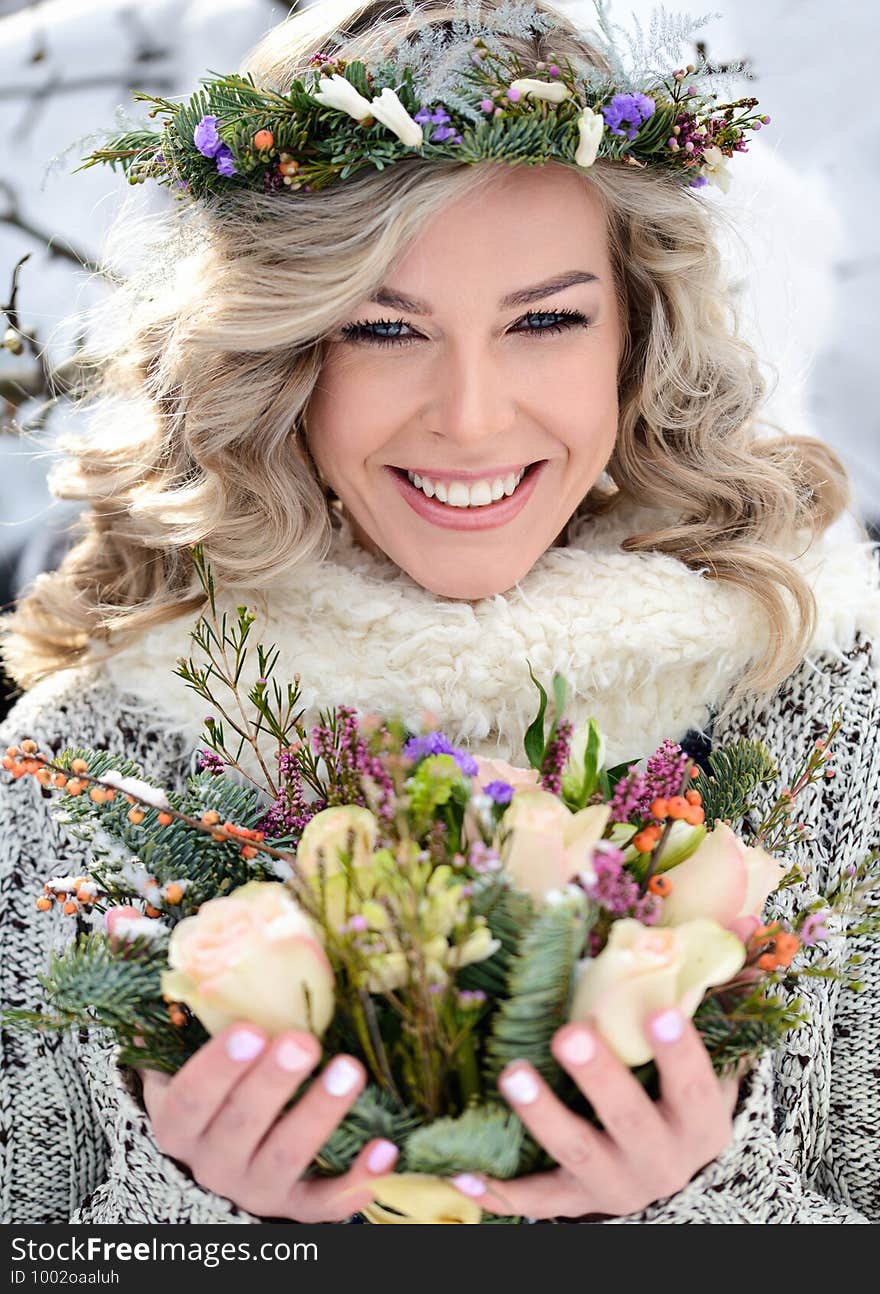 Attractive woman with white teeth and a perfect smile holds a bouquet of roses and fir branches. Happy sincere winter outdoor