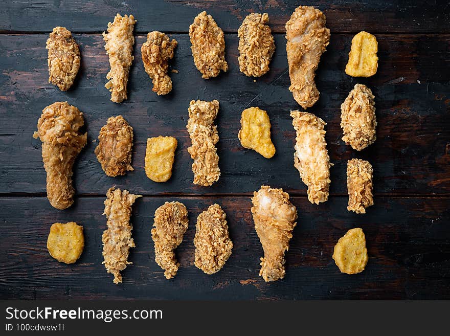 Homemade crispy fried chicken parts on old dark wooden table, flat lay