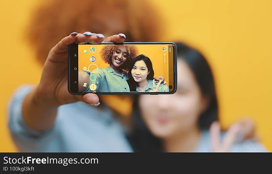 Two young girls, best friends using smartphone to take photo. Making grimaces