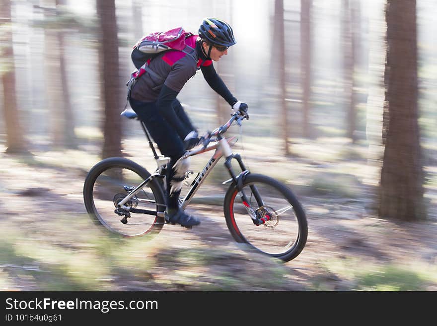 Man riding a mountain bike in a forest on a sunny day with fog