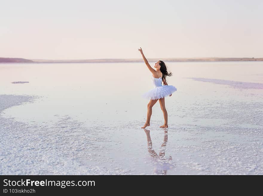 Girl ballerina in a ballet dress dances in the water