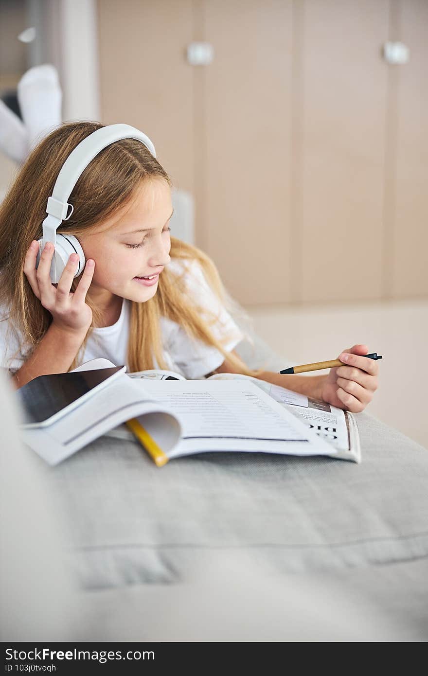 Learner of English taking pleasure in listening to the melodies through headphones while pointing an eco-pen to the workbook. Learner of English taking pleasure in listening to the melodies through headphones while pointing an eco-pen to the workbook