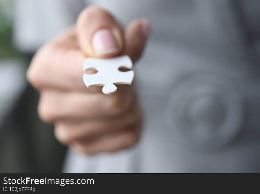 Male fingers are holding one white puzzle.