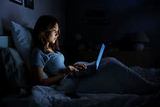 Woman Using A Laptop In Her Bed Royalty Free Stock Images