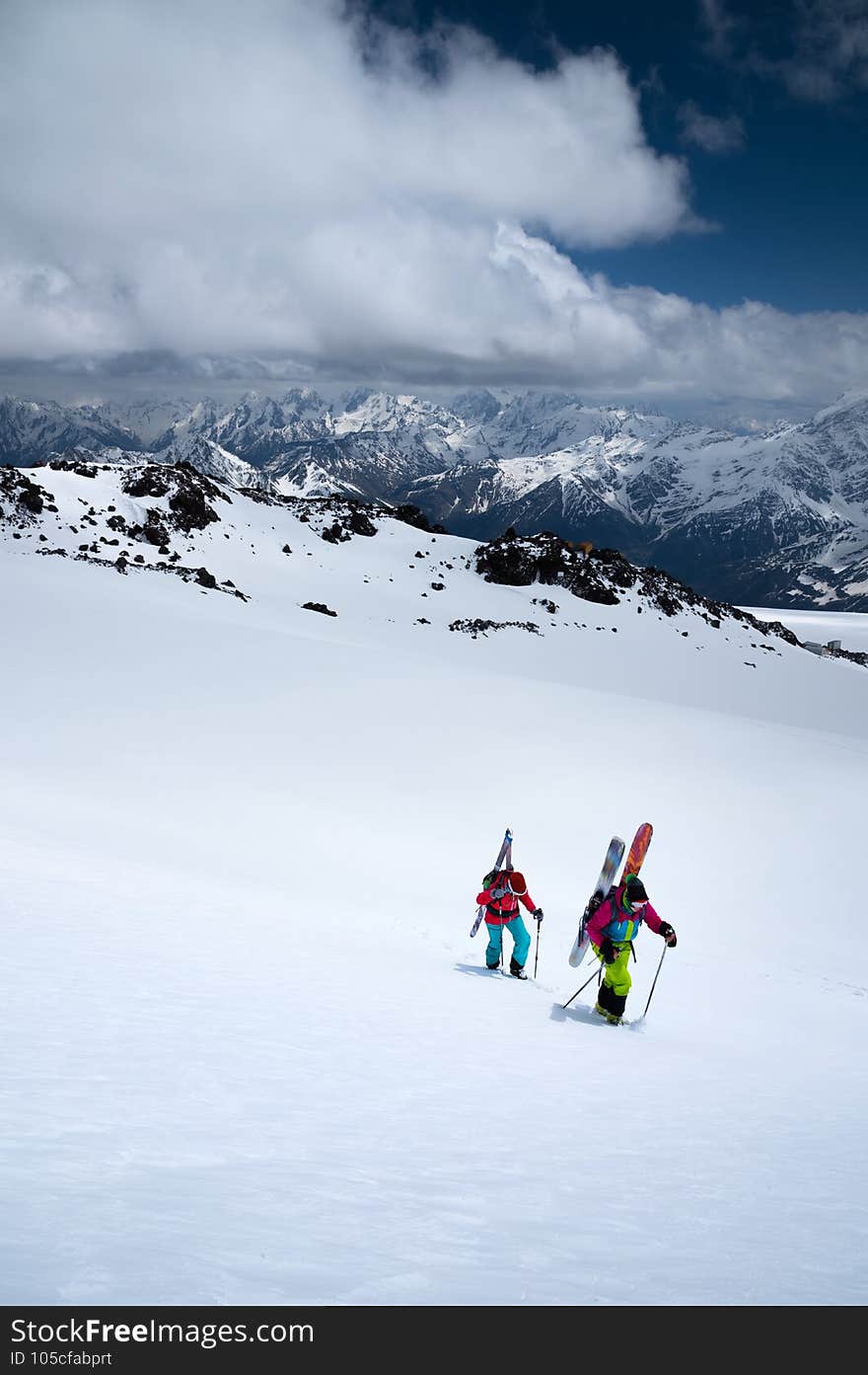 Two young women sportswomen backcountry climbing in the snow high in the mountains for freeride skiing off pistes