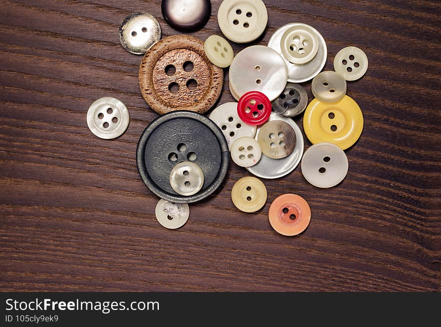 Overhead shot of old clothing buttons on a dark wooden background