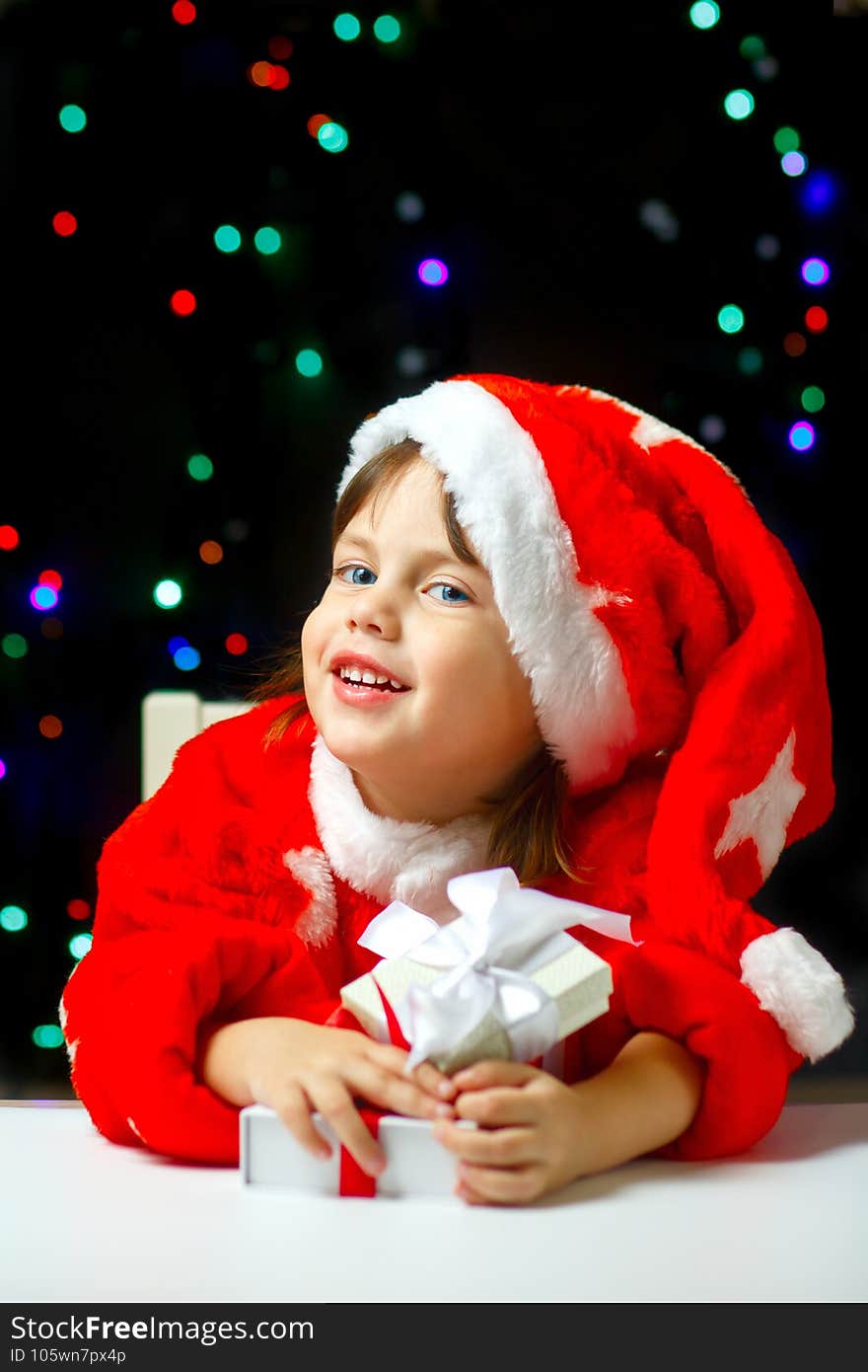 Little Santa Claus with Christmas gifts is smailing. Four year old baby in festive santa costume