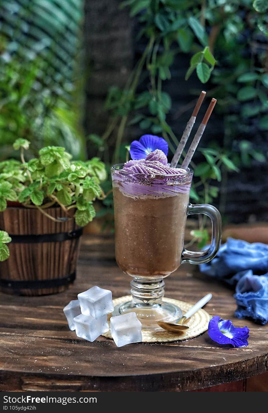 A glass of Chocolate Milky Iced with topped Taro Mousse. On a wooden table. A glass of Chocolate Milky Iced with topped Taro Mousse. On a wooden table.