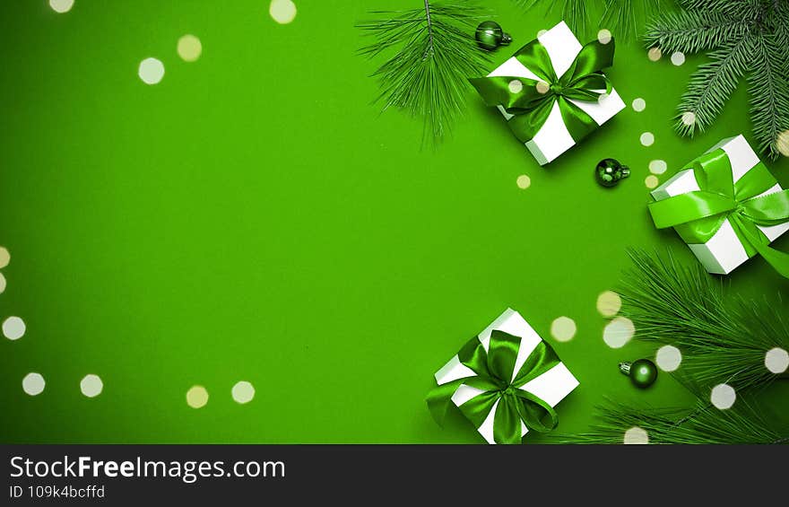 Happy new year. White gifts with emerald bow, green balls and sparkling lights in xmas decoration on greenish background for