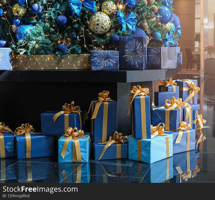 Christmas seasons. Christmas decorations. Beautiful decorated tree with presents gift boxes on floor. Close up of ornament on Chri