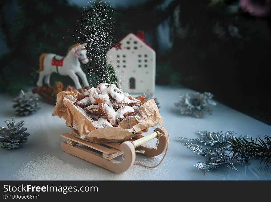 Firewood with sugar. Crunchy Cookies in the shape of icicles on a toy sled in a Christmas composition. Christmas greeting card