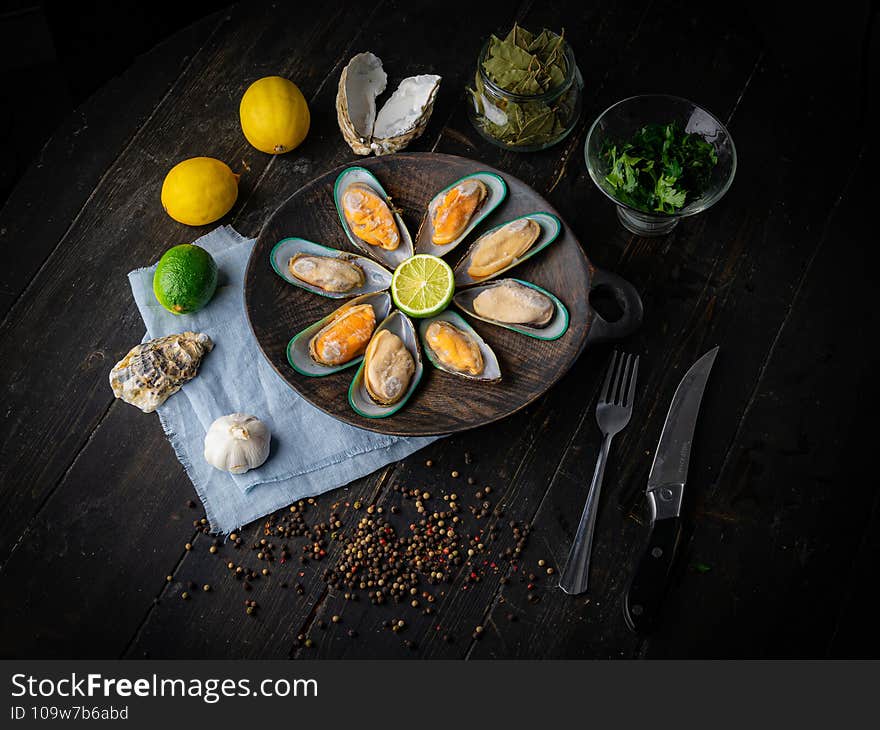 Wooden bowl with raw iced kiwi mussels with lime and lemon