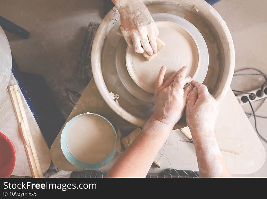 Female hands crafting a pottery cup on a potter`s wheel. Handmade and crafting