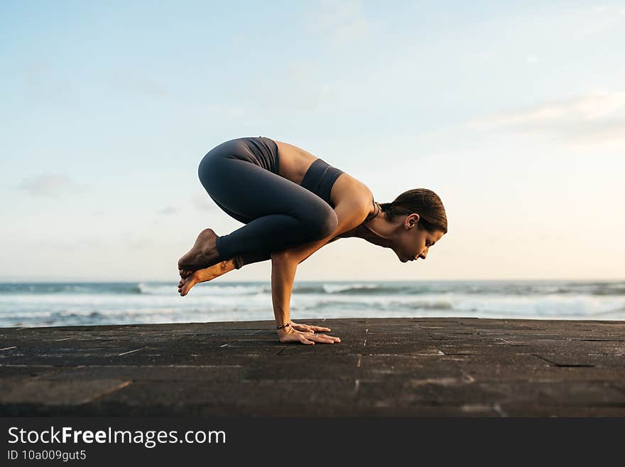 Young woman doing yoga asana in the nature with the ocean view.