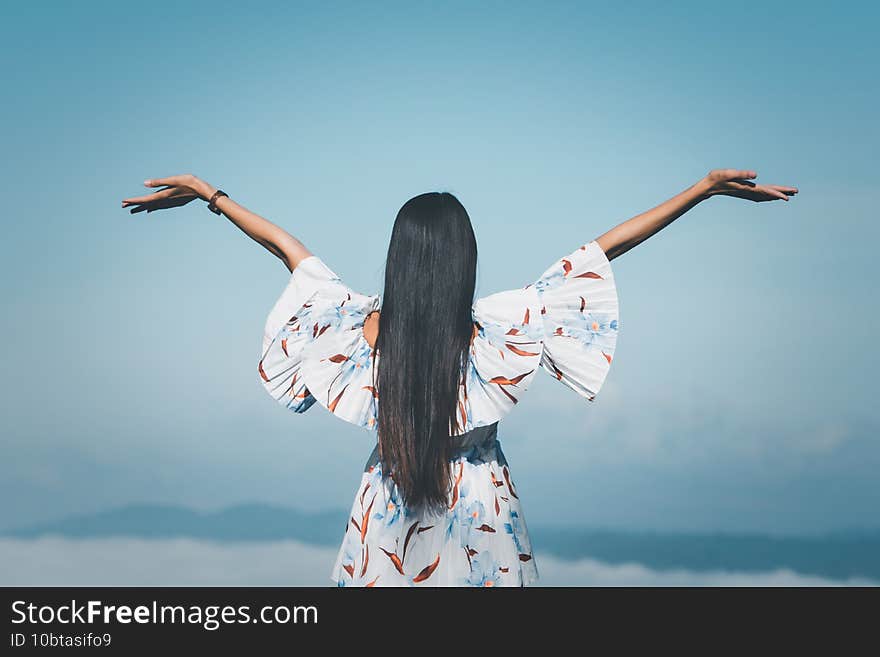 Traveler woman standing with raised hands looking Foggy in the mountains at sunrise