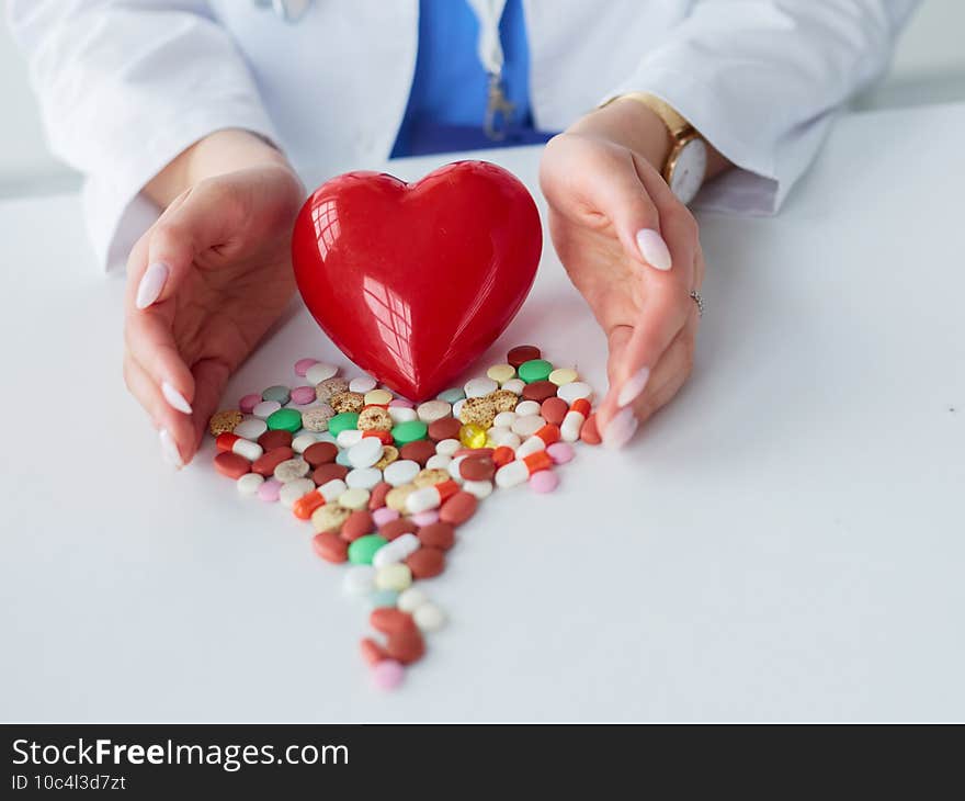 Cardiologist with red heart and stethoscope at table