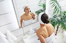 Beautiful Young Latin American Woman Applying Her Blush Or Face Powder Before Mirror Royalty Free Stock Photos