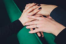 Two Man And Three Women Holding Hands On A Table Implying A Polyamory Relationship Or Love Triangle. Royalty Free Stock Photography