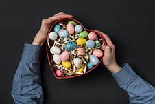 Children Holding A Heart Shaped Box With Colorful Easter Eggs. Black Background. Gift For Easter Stock Images