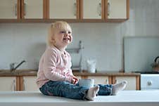 Portrait Of Smiling Blonde Child With Cup On Kitchen Table. Breakfast In Family Royalty Free Stock Photos