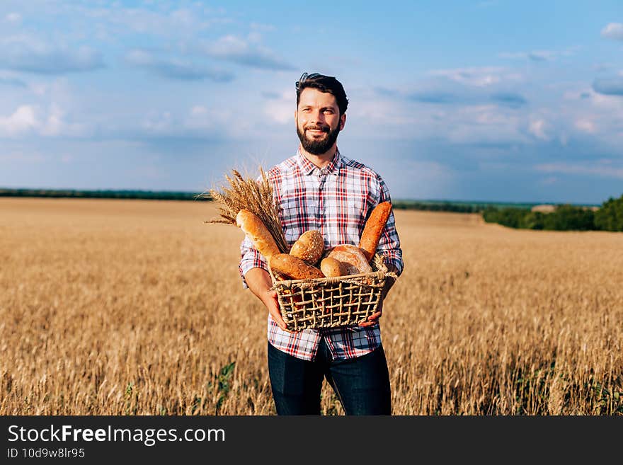 A happy baker holding a wicker basket in her hands, with a wheat field in the background