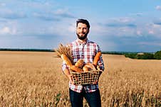 A Happy Baker Holding A Wicker Basket In Her Hands, With A Wheat Field In The Background Royalty Free Stock Photo