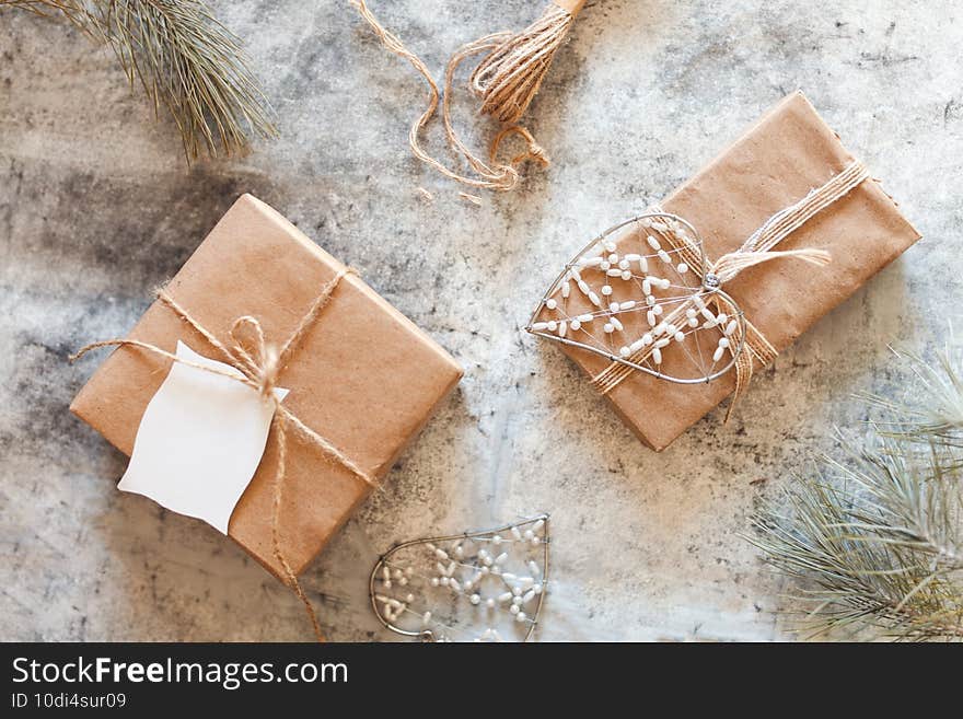 Scandinavian style winter background - brown paper wrapped CHristmas gifts with pine cones and jute rope on white winter