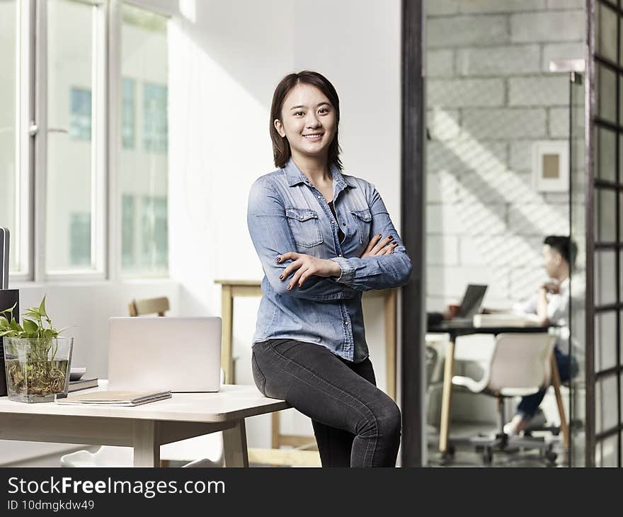 Portrait of a young asian business woman looking at camera smiling arms crossed. Portrait of a young asian business woman looking at camera smiling arms crossed