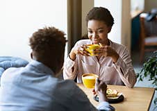 Handsome Black Man With His Girlfriend Enjoying Aromatic Coffee And Having Friendly Conversation At City Cafe Royalty Free Stock Image