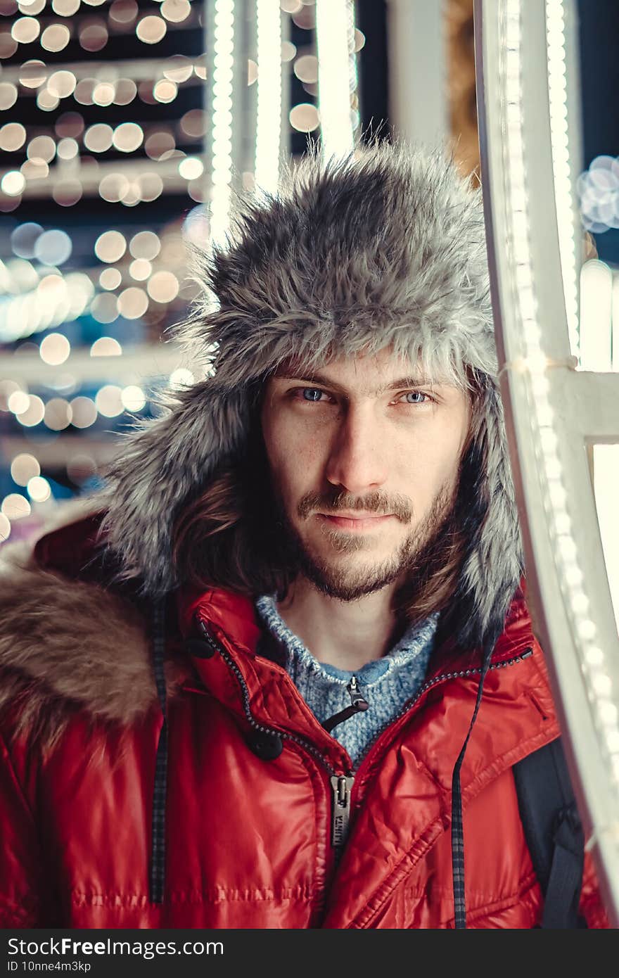 a guy in a hat on the street in winter against the background of lights garlands. a guy in a hat on the street in winter against the background of lights garlands