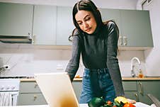 Young Caucasian Woman Use Tablet Computer In The Modern Kitchen, Preparing Salad, Read Recipe Royalty Free Stock Photography