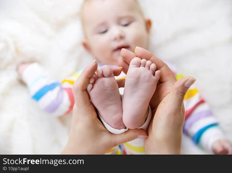 The mother holds the legs of her baby. Selective focus.