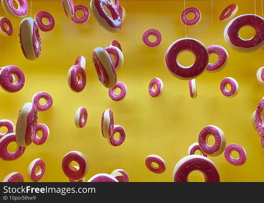 Closeup of donut figures hanging from ropes against a yellow background