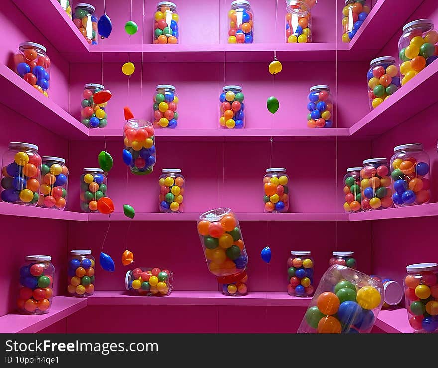 Closeup of colorful plastic ocean fun balls in jars on shelves hanging in a pink room